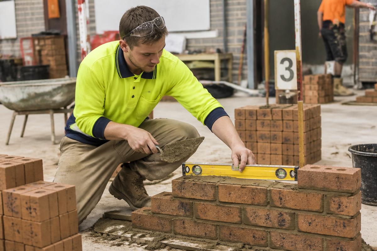 Mason laying bricks during a construction trade test